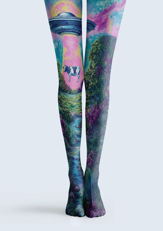 Blue, purple and green printed tights with a UFO lifting a cow above a surreal countryside landscape