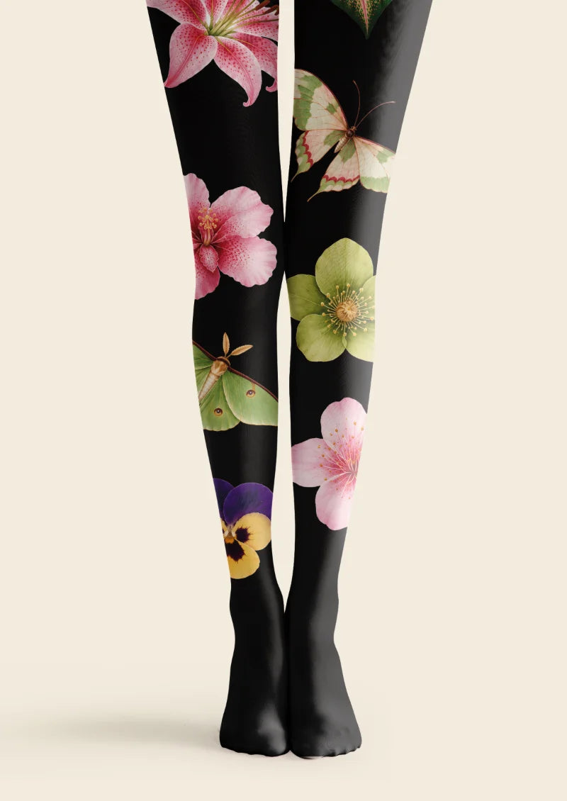 Black tights with oversized pink flowers, green leaves, moth motifs, and yellow and purple floral accents