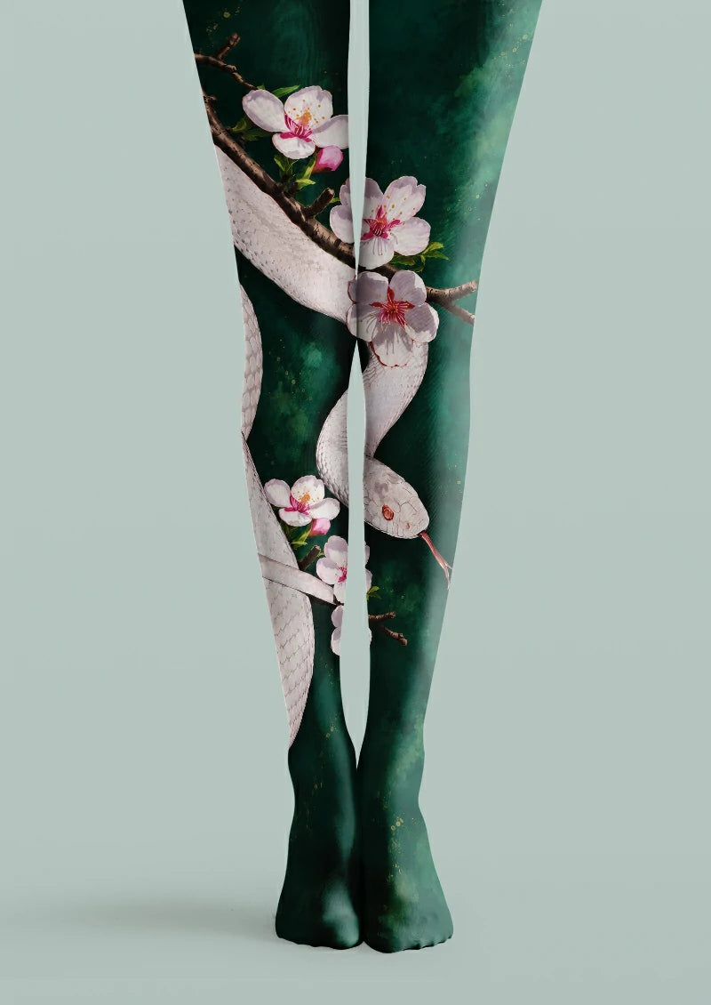 Green printed tights with a pale snake, visible scale details, brown branches and pink blossoms.