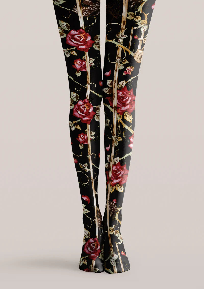 Black printed tights with red roses, brown thorny stems, shaded leaves, and scattered red petals along both legs.