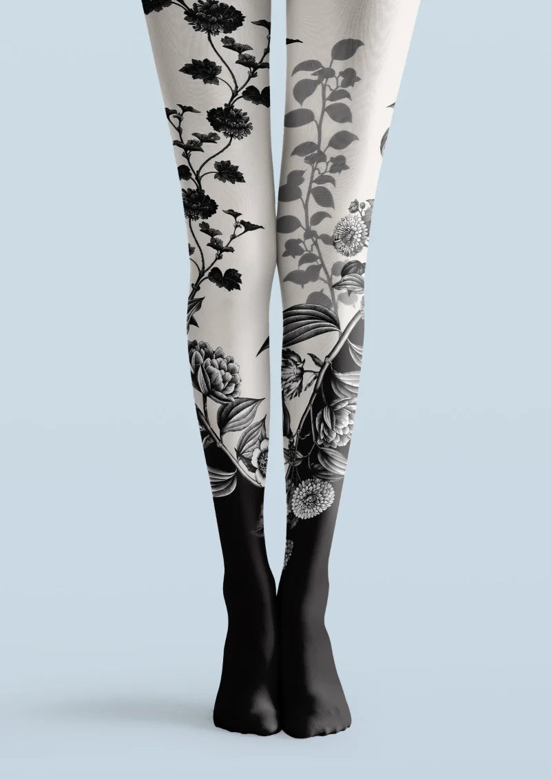 Black and white printed tights with black botanical floral motifs and a dark lower-leg finish.
