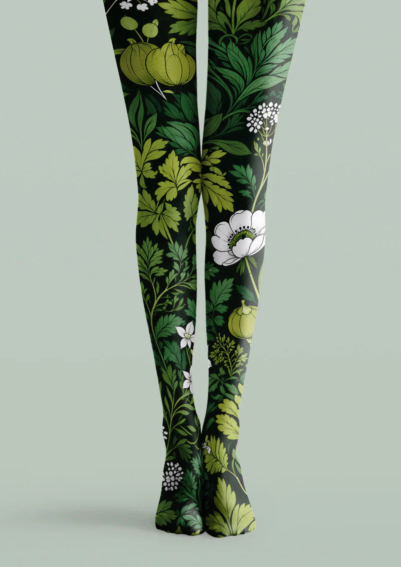 Black printed tights with green botanical foliage, yellow-green fruit motifs, and white flowers.