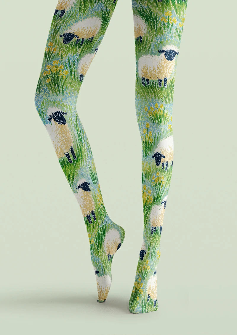 Green printed tights with cream sheep, grass, small yellow flowers, and pale blue field details