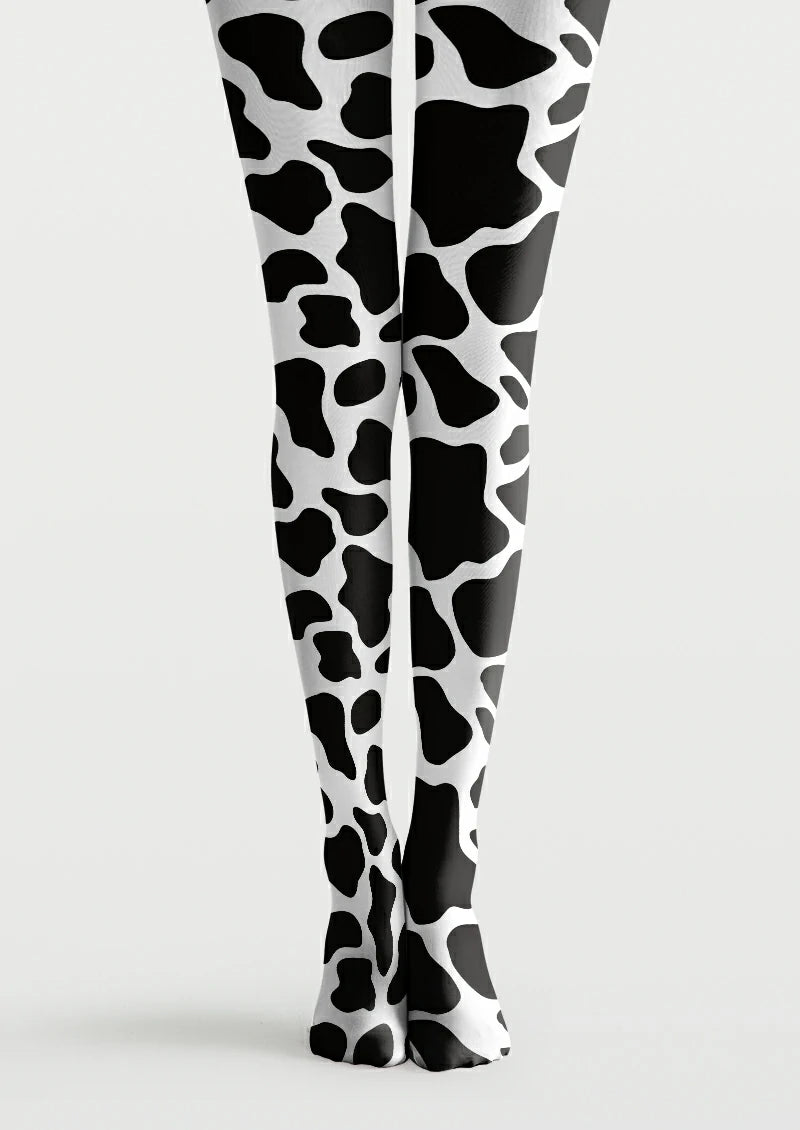 Black and white printed tights with large irregular cow patches and smaller rounded markings across both legs and feet.