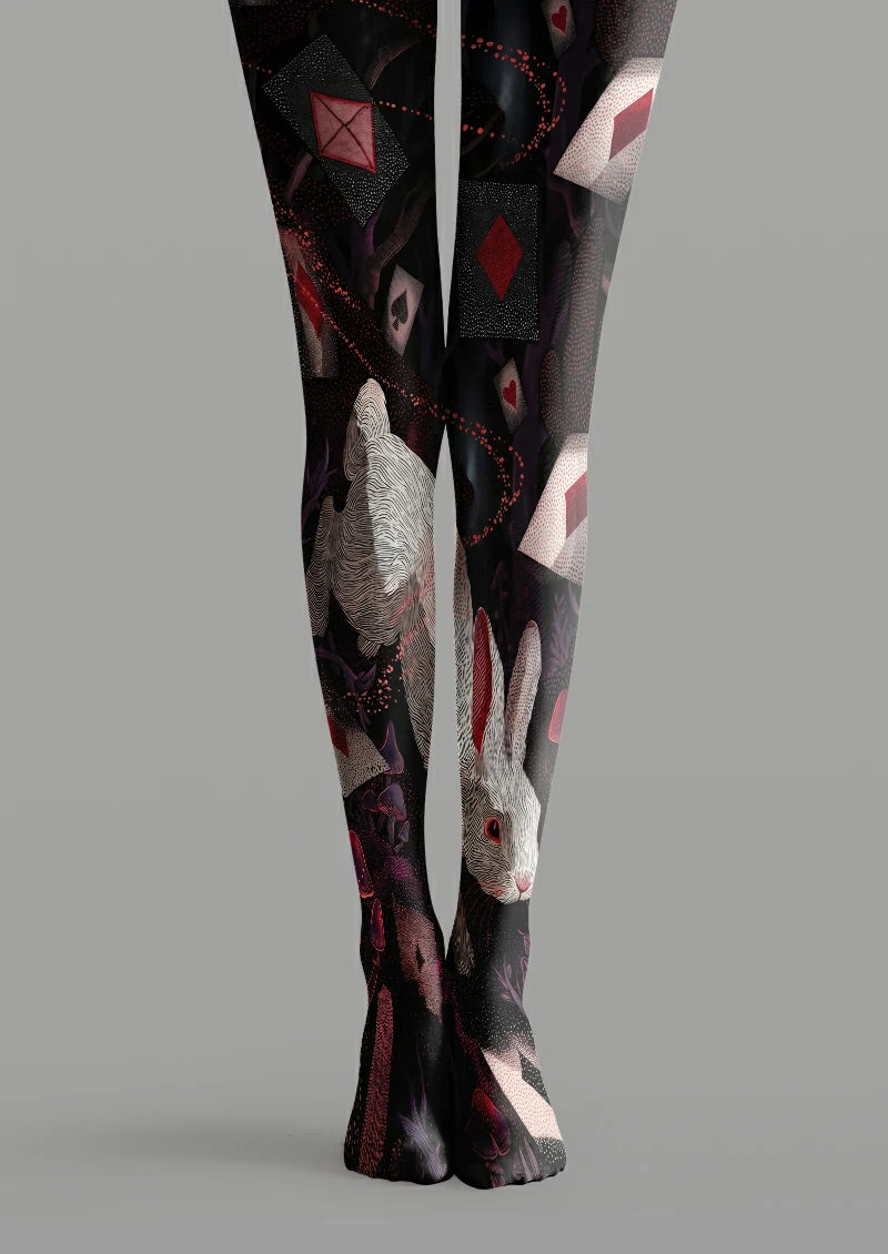 Black printed tights with a large white rabbit, red and black playing card symbols, mushrooms and purple foliage.