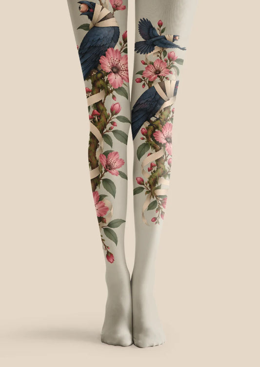 Ivory printed tights with bandaged navy birds, oversized eyes, pink blossoms, leafy branches, and curling cream ribbons