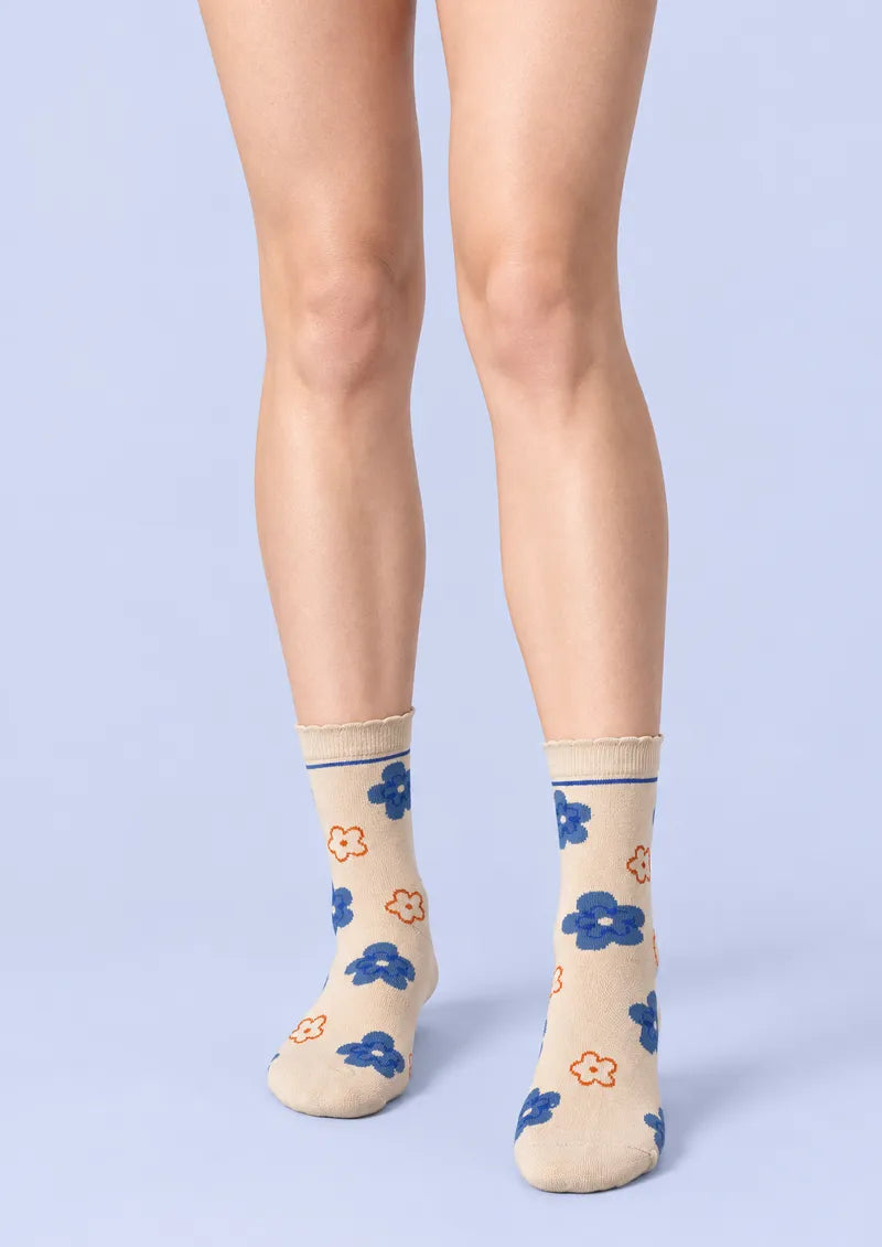 Top view of ivory Crew Socks with large blue flowers, small orange outlined flowers, and a scalloped cuff.
