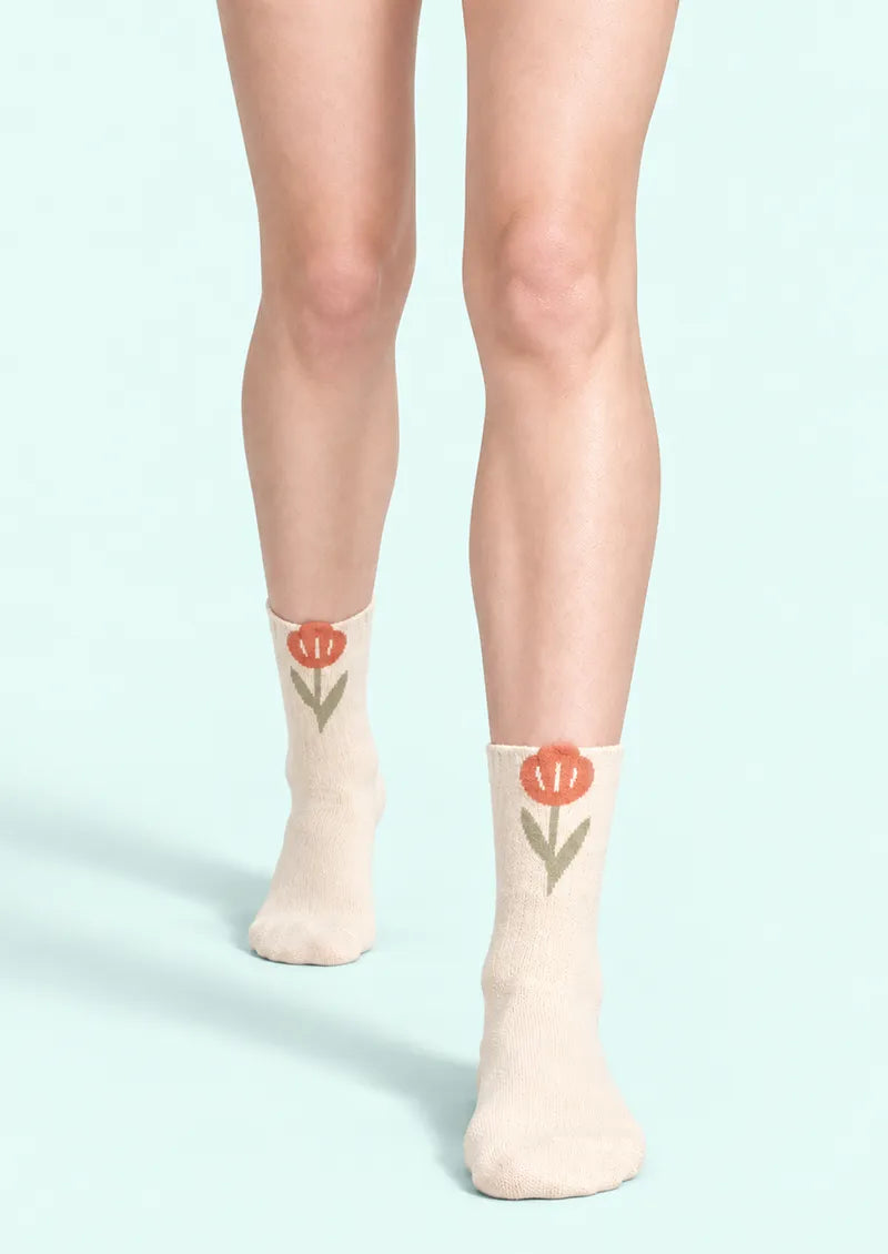 Top view of ivory Crew Socks with orange tulip appliques at the cuffs and green stems and leaves.