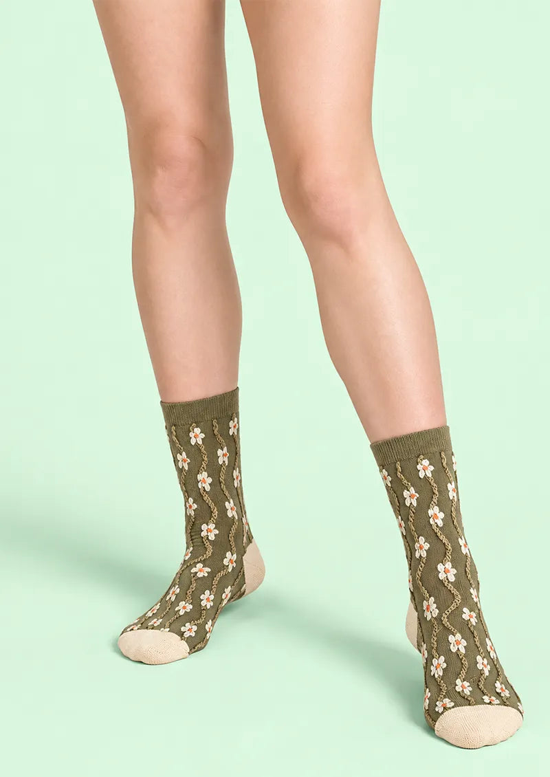 Top view of green Crew Socks with white daisy accents, orange centers, and contrast ivory toes and heels.