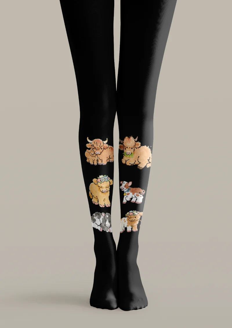 Black printed tights with brown Highland cows, flower crowns, and smaller white-marked calves arranged along the lower legs.