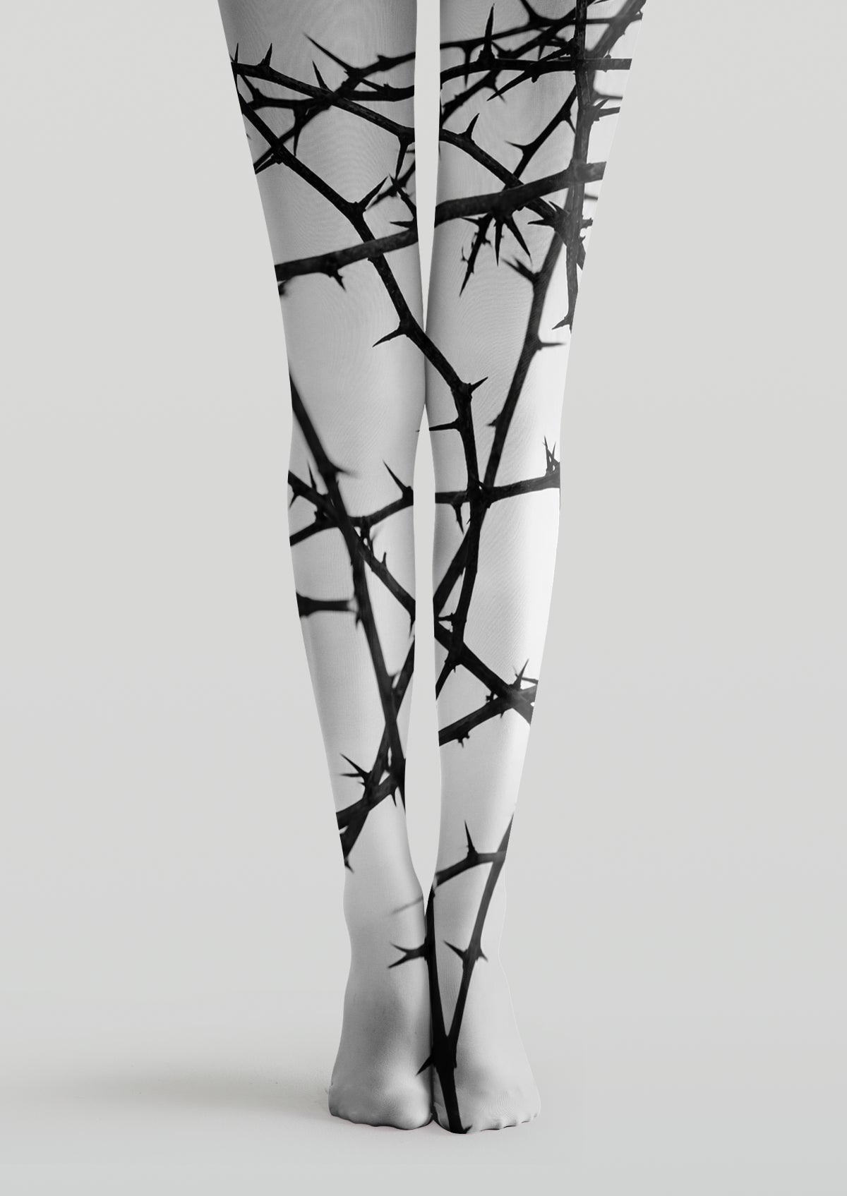 White printed tights with tangled black thorny branch patterns across legs and feet