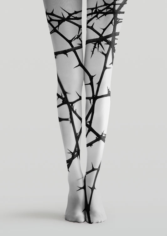 White printed tights with tangled black thorny branch patterns across legs and feet