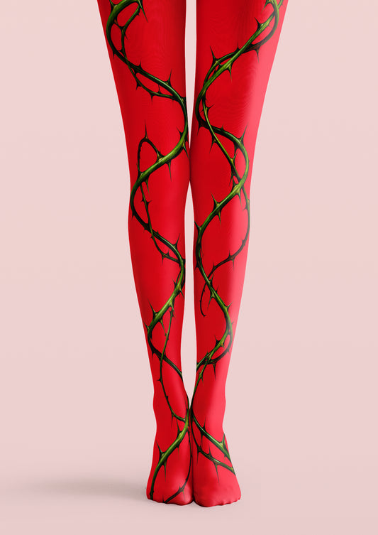 Red printed tights with winding green thorn vines and black detailing extending down both legs onto the feet