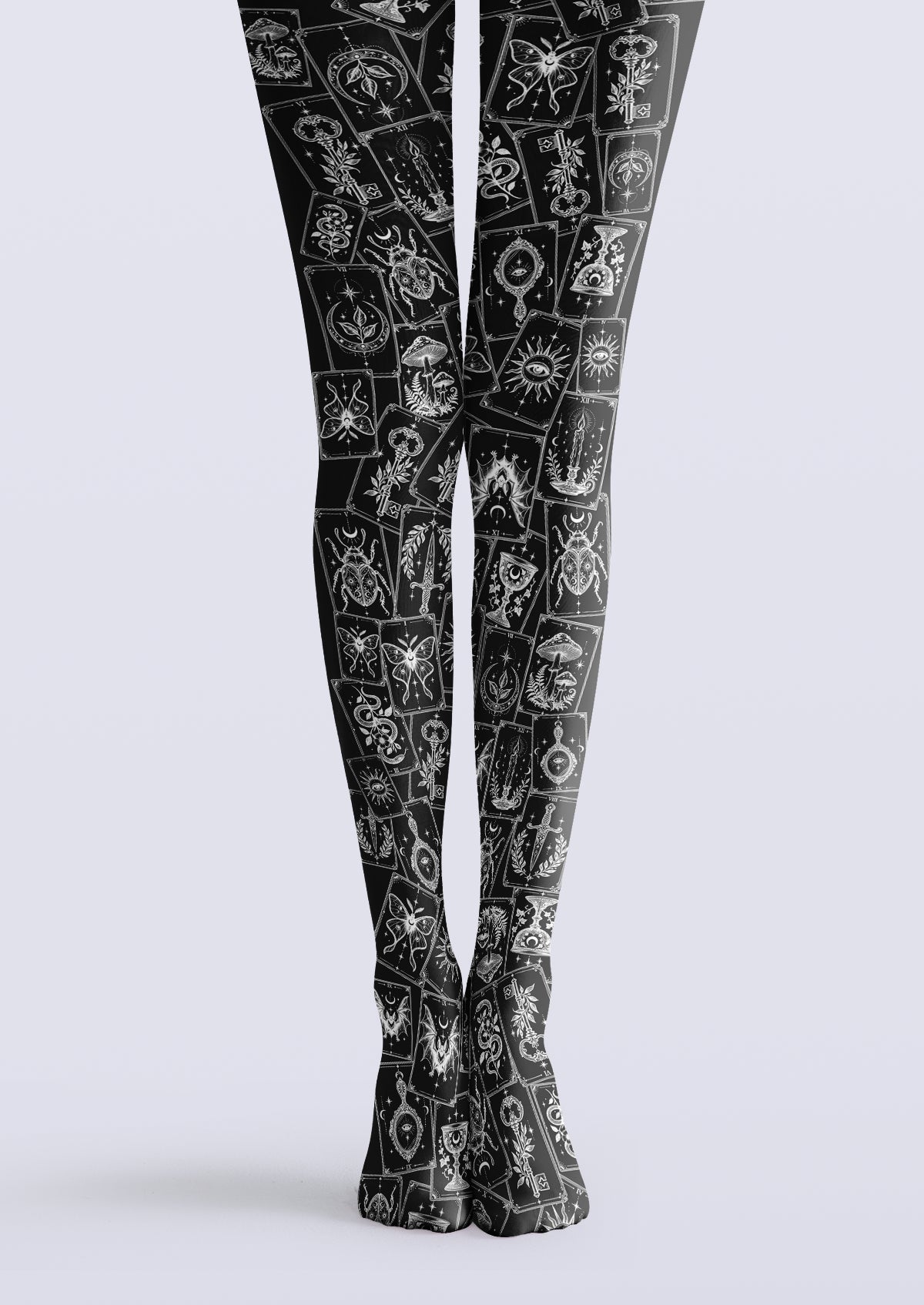 Black printed tights with overlapping cards in white linework, including moths, keys, suns, and crescent moons